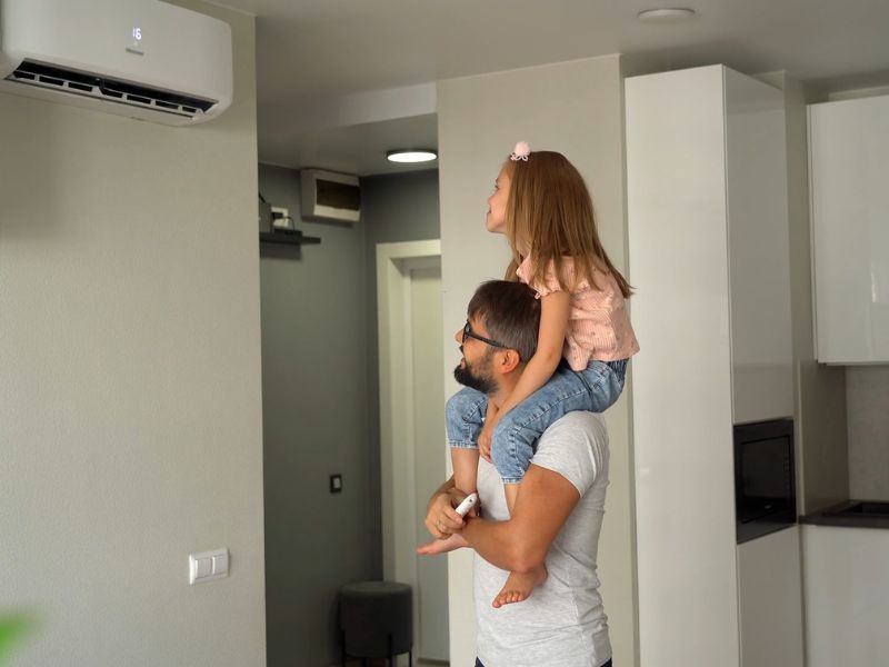 tata koji nosi ćerku na ramenima sa smeškom podešava temperaturu klime