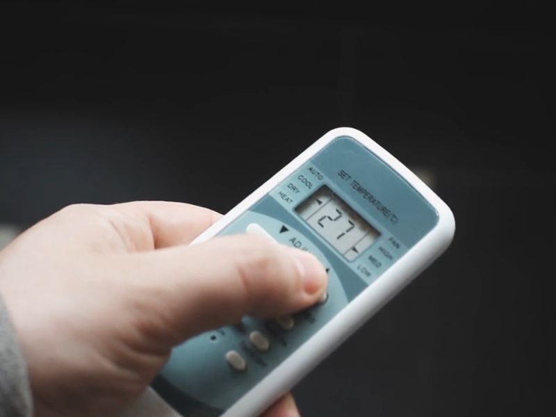 osoba koristi daljinski za klima uređaj