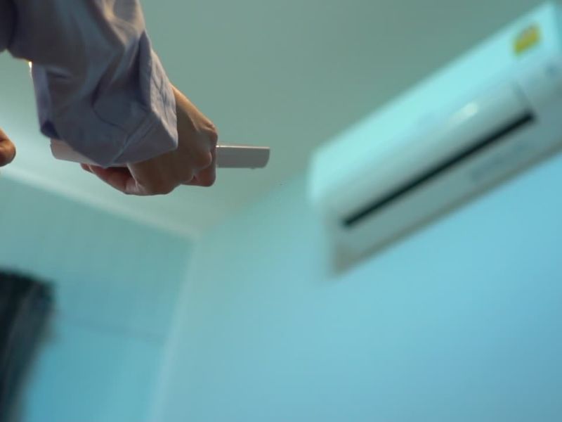 muškarac koristi daljinski uređaj i podešava nešto na klimi